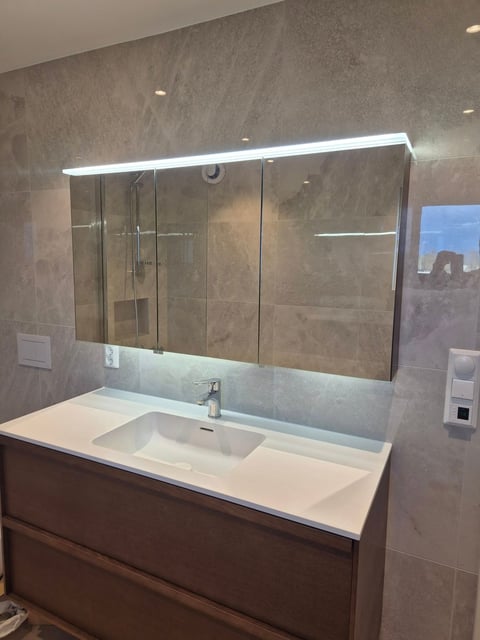 Modern bathroom vanity with integrated sink, LED-lit mirror cabinet, and gray tile walls