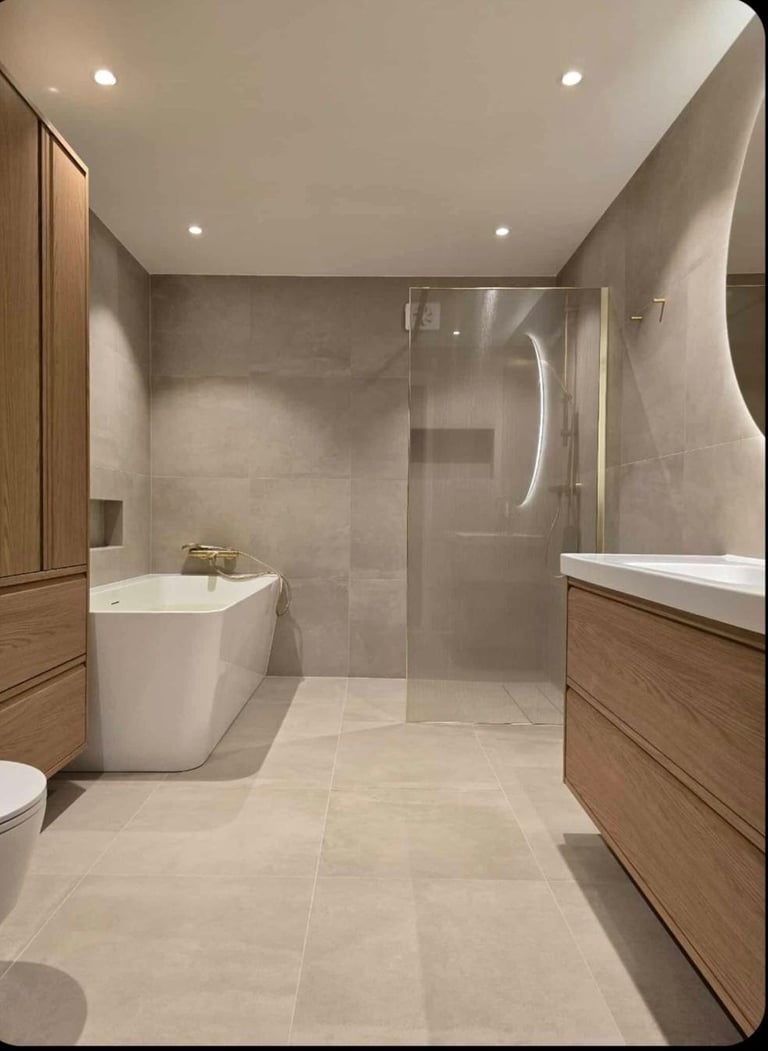 Modern bathroom with light stone flooring, wooden cabinetry, white soaking tub, and walk-in shower with glass enclosure